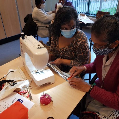 Twee vrouwen werken achter de naaimachine