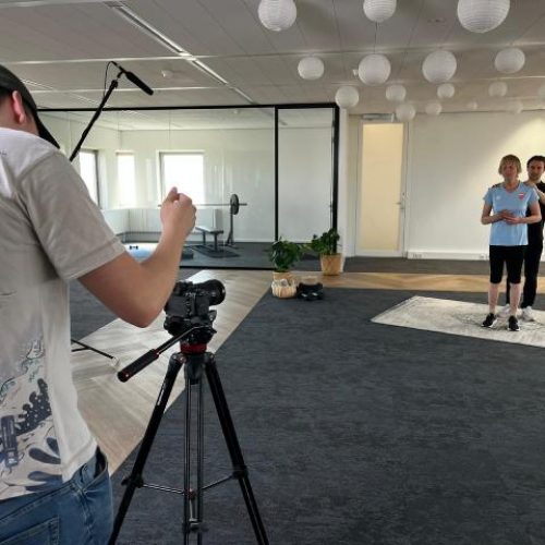 Een cameraman en een sporter tijdens de opnames voor de Uniek Sporten Thuis-app