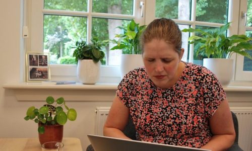 Wendela zit in een stoel met haar laptop op schoot.