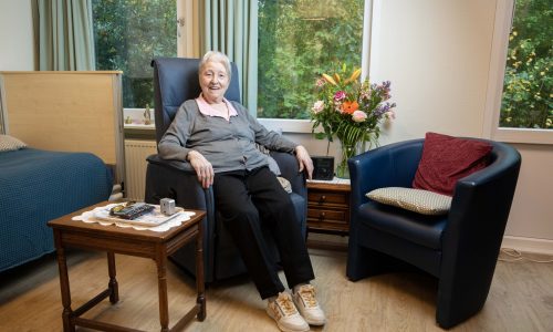 Mw. Van Zuijdam zit in de stoel op haar kamer.