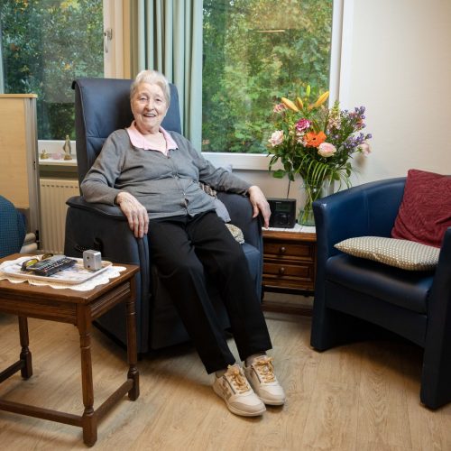 Mw. Van Zuijdam zit in de stoel op haar kamer.