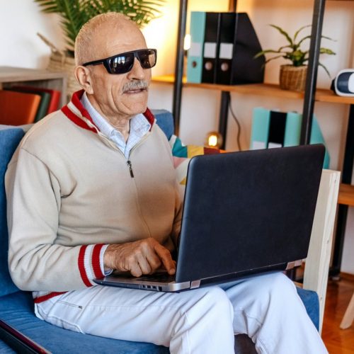 Blinde man zoekt op laptop naar info.