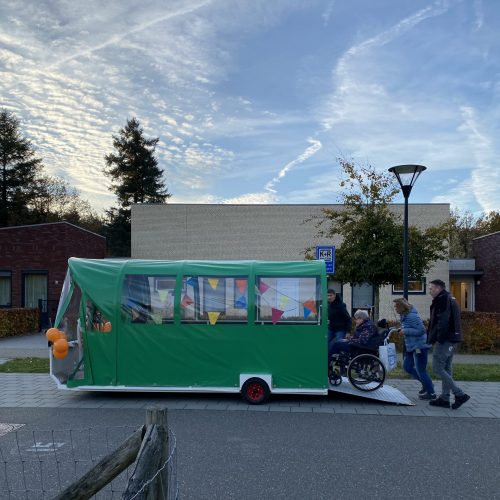 Bewoners worden in hun rolstoel in de mo-car gereden.