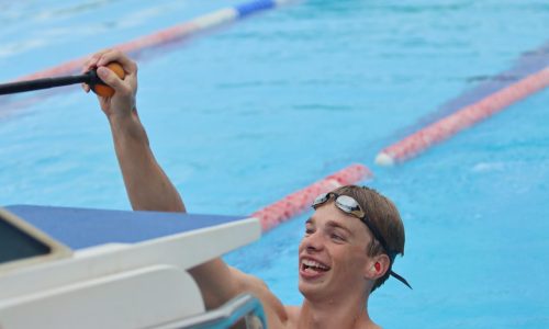Paralympisch zwemmer Rogier Dorsman in het zwembad, hij pakt het balletje aan de hengel vast en lacht.