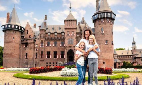 Een moeder staat met haar twee dochtertjes voor een kasteel.