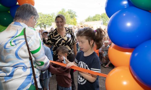 Twee leerlingen van de school van Bartiméus knippen het lint door samen met een mevrouw van de gemeente.