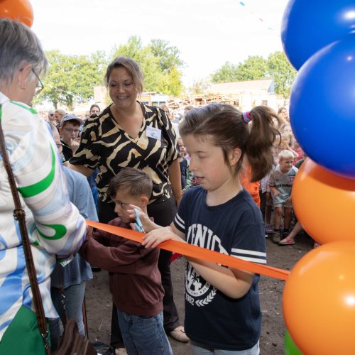Twee leerlingen van de school van Bartiméus knippen het lint door samen met een mevrouw van de gemeente.