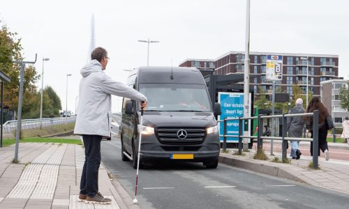 Slechtziende man maakt het oversteekgebaar met zijn witte stok.